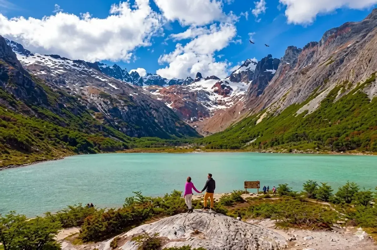 Turistas frente a la Laguna Esmeralda con montañas nevadas y agua turquesa en Ushuaia